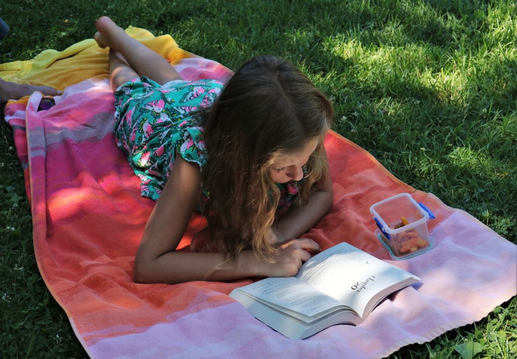 girl reading blanket grass skylar zilka unsplash